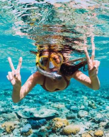 Happy young woman swimming underwater in the tropical ocean